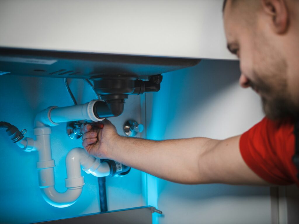 Tradesperson repairing a pipe inside a wall
