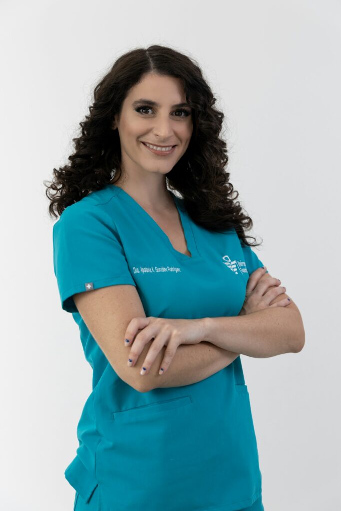 Medical assistant in teal scrubs standing with arms crossed
