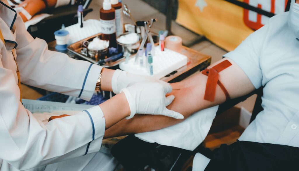 Phlebotomist in white gloves drawing blood from a patient's arm