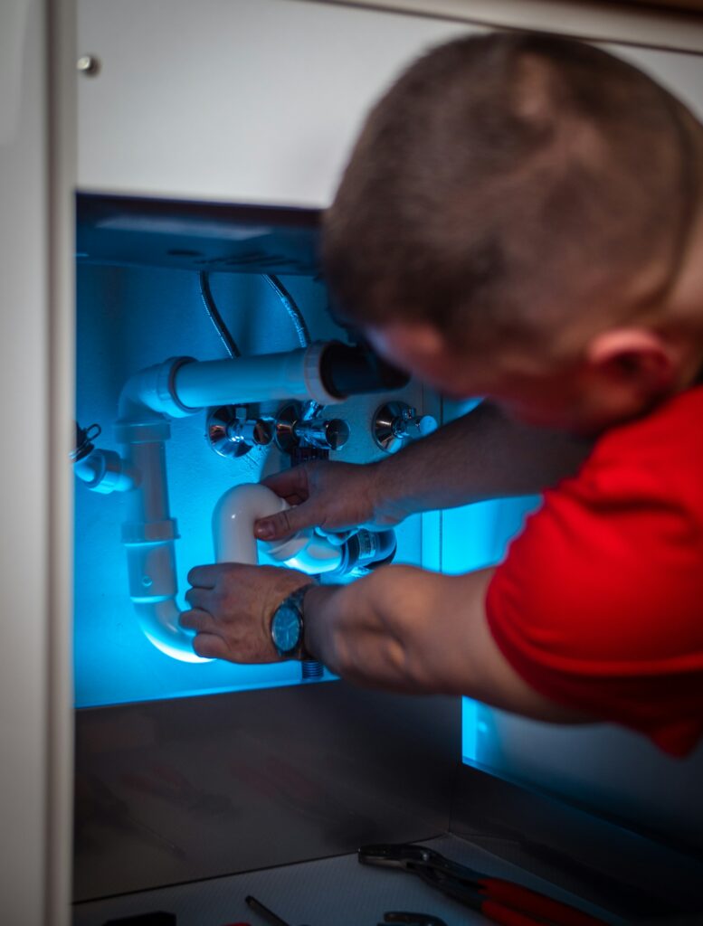 Plumber working on a pipe under a sink cabinet