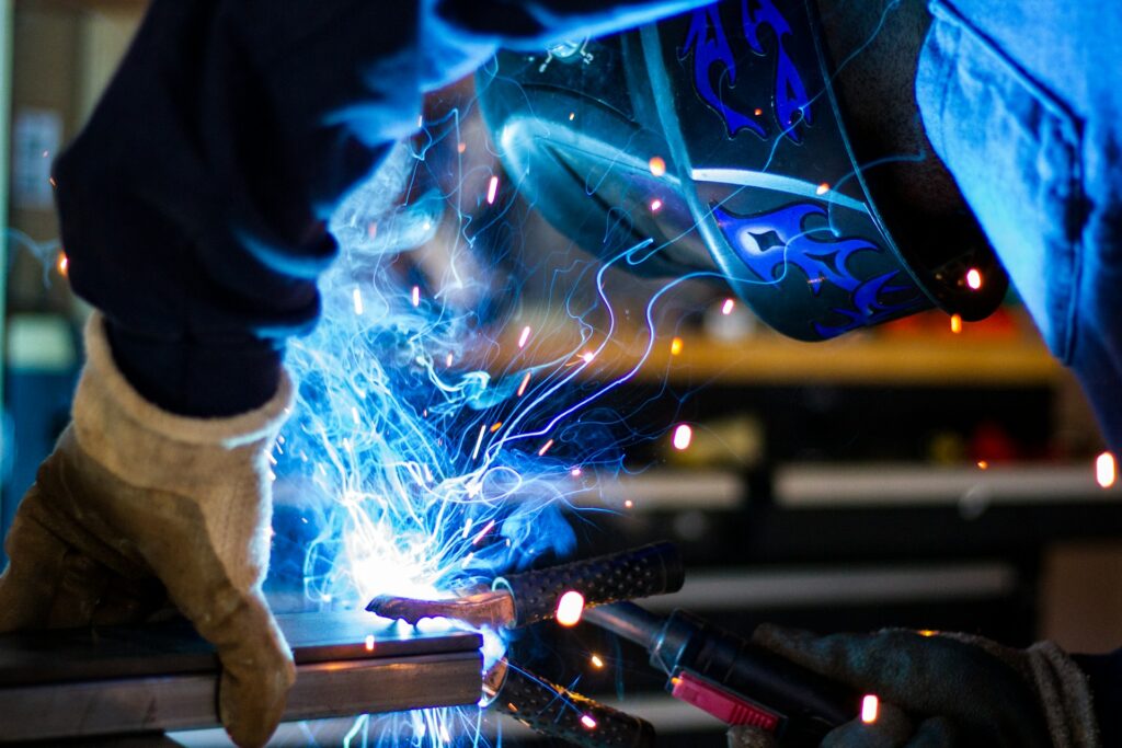 Welder in a protective helmet and gloves working on metal with sparks
