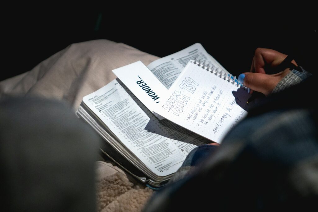 Person writing study notes in a notebook to prepare for a certification exam